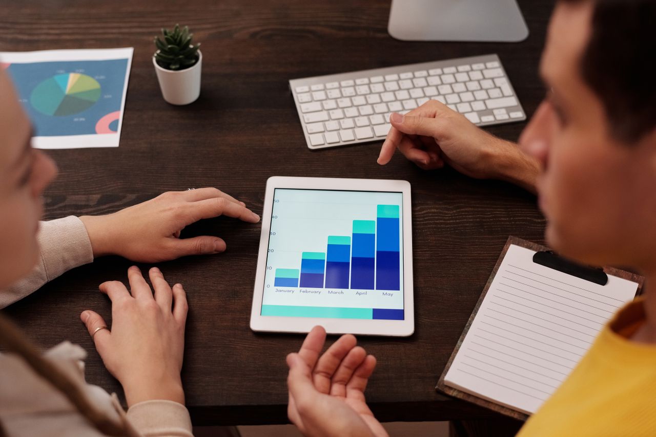 The SEO Process (And Audit) Nobody Explains Properly Team members discussing digital graphs on a tablet in a modern office setting.
